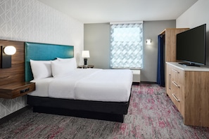A hotel room with a bed, a TV, a desk, and a window with a view. - Home2 Suites by Hilton Rapid City (Rapid City)