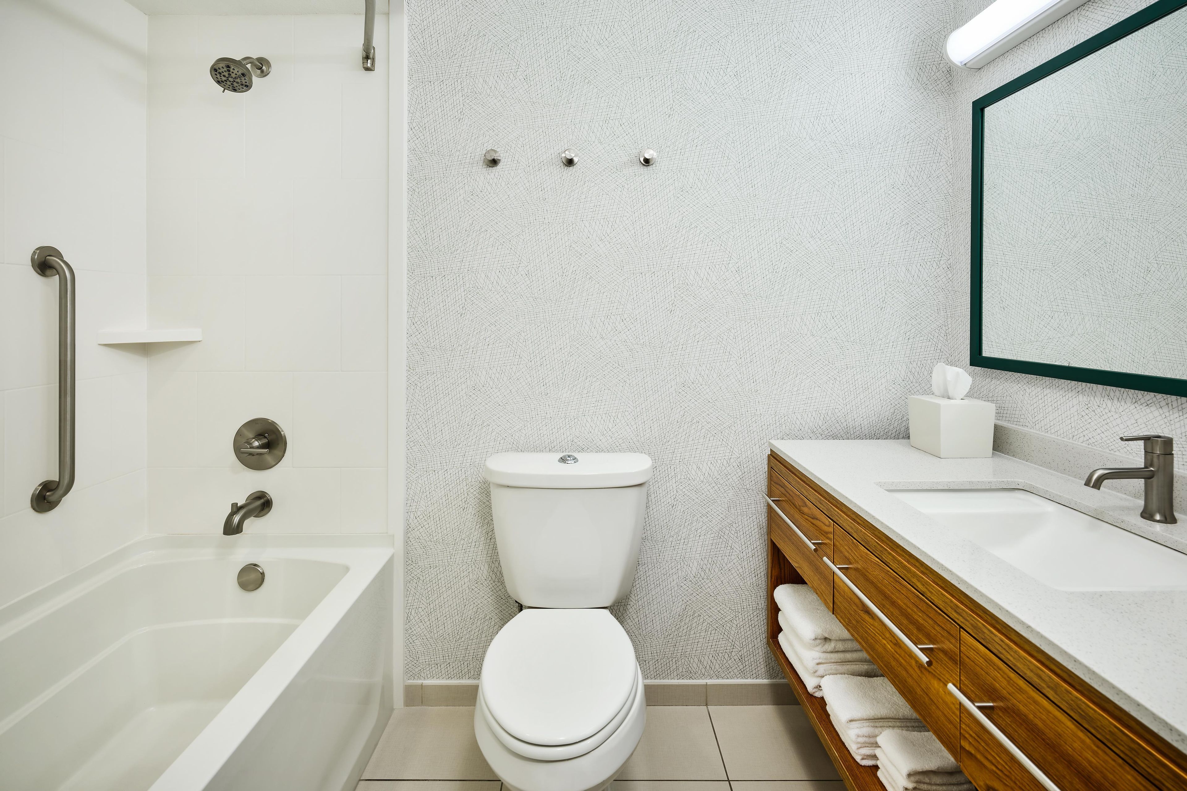 Een badkamer met een bad, toilet, wastafel en spiegel.