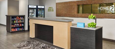 Uma área de recepção de hotel com balcão, minibar e placa na parede.