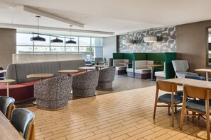 Un intérieur moderne avec des espaces aménagés pour s’asseoir, des tables et un mur orné de motifs.