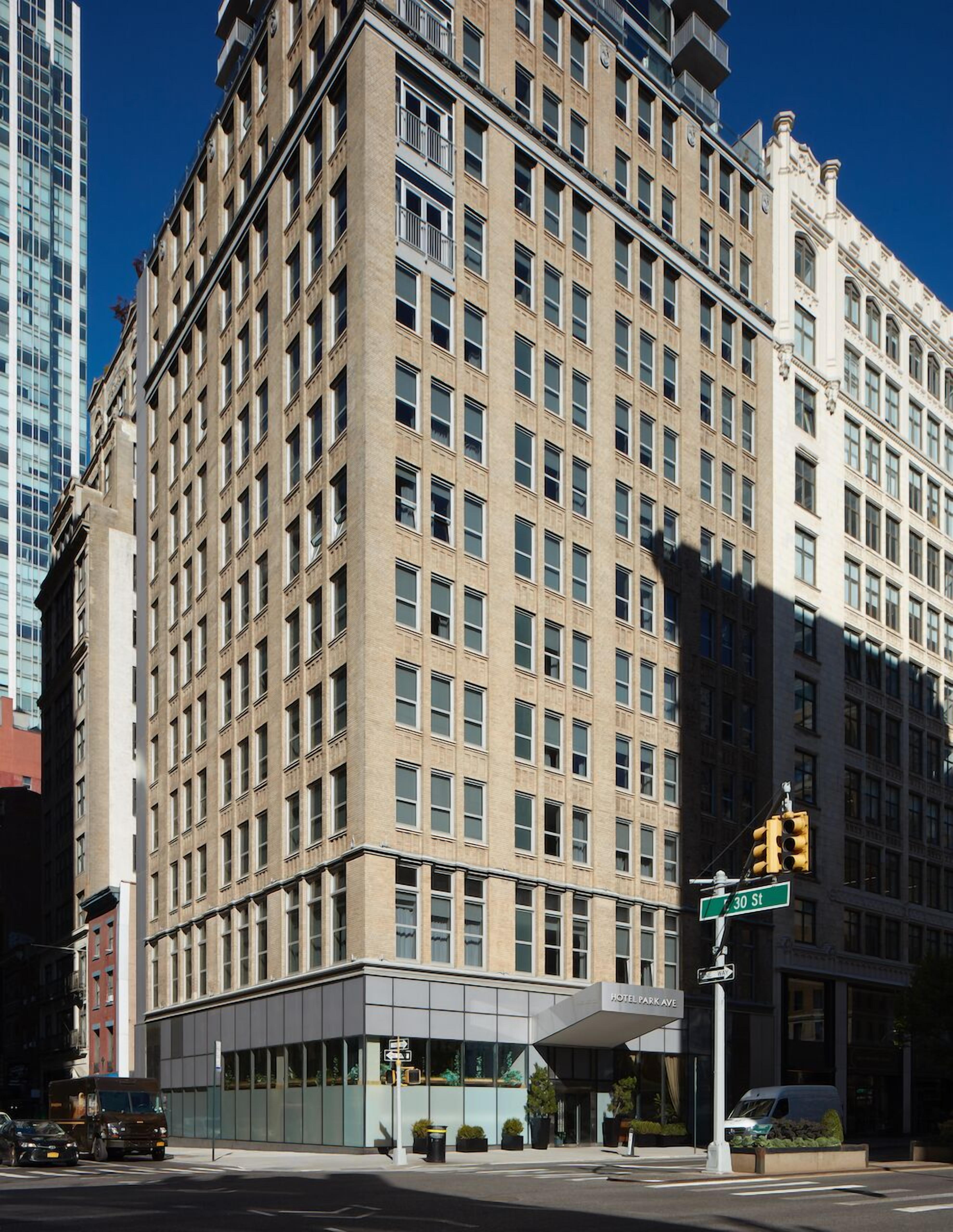 Un hotel de varios pisos con un estilo arquitectónico clásico, que presenta una entrada destacada en esquina y una fachada moderna de vidrio.