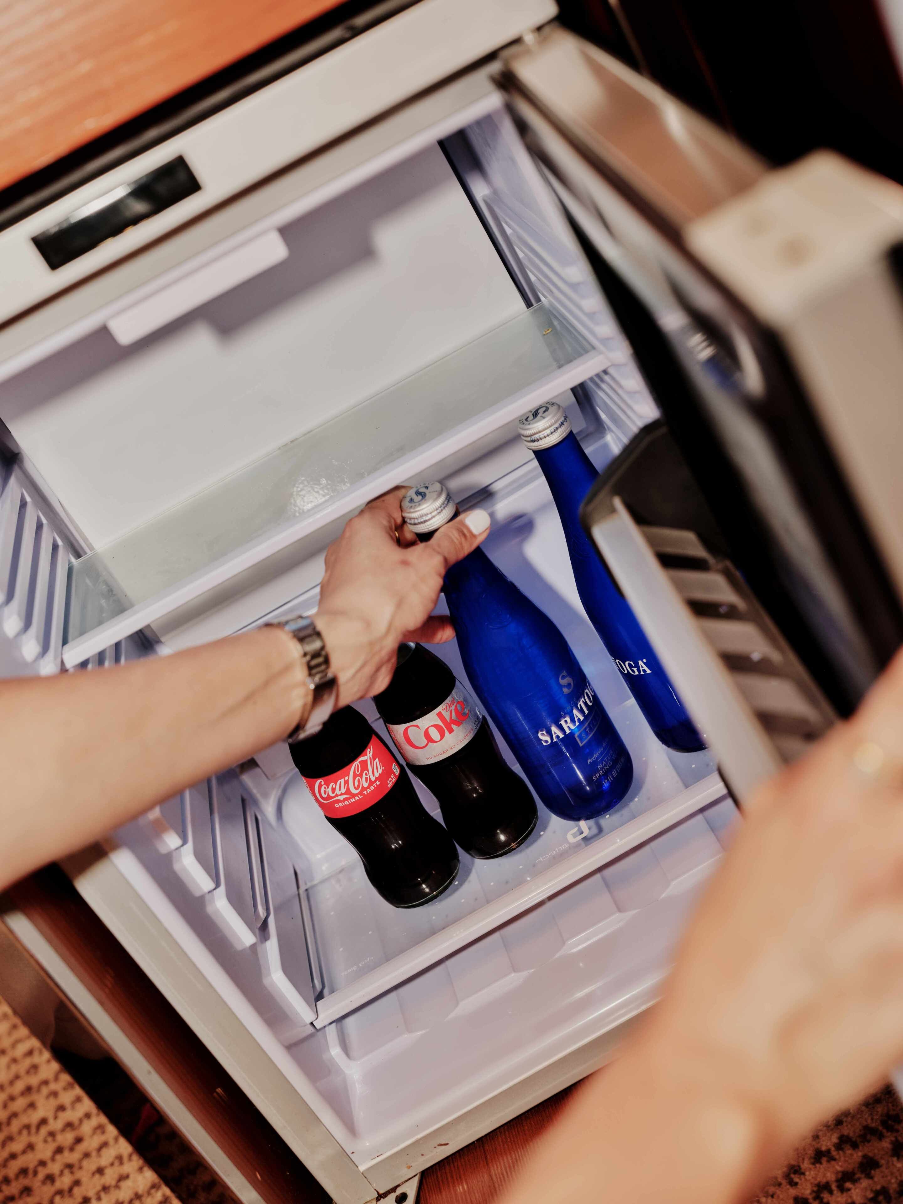 A hand placing bottles in a refrigerator.