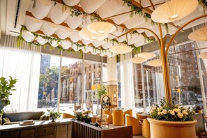 Un interior moderno con ventanas amplias, una zona de estar con sofás y sillones, y lámparas colgantes con plantas.