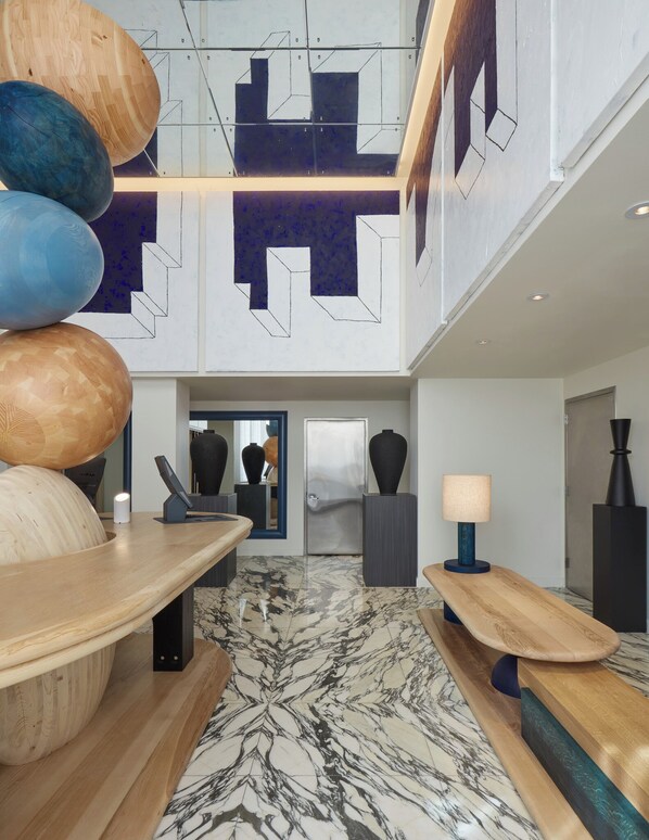 Un vestíbulo moderno con piso de mármol, mobiliario de madera y arte abstracto en la pared.