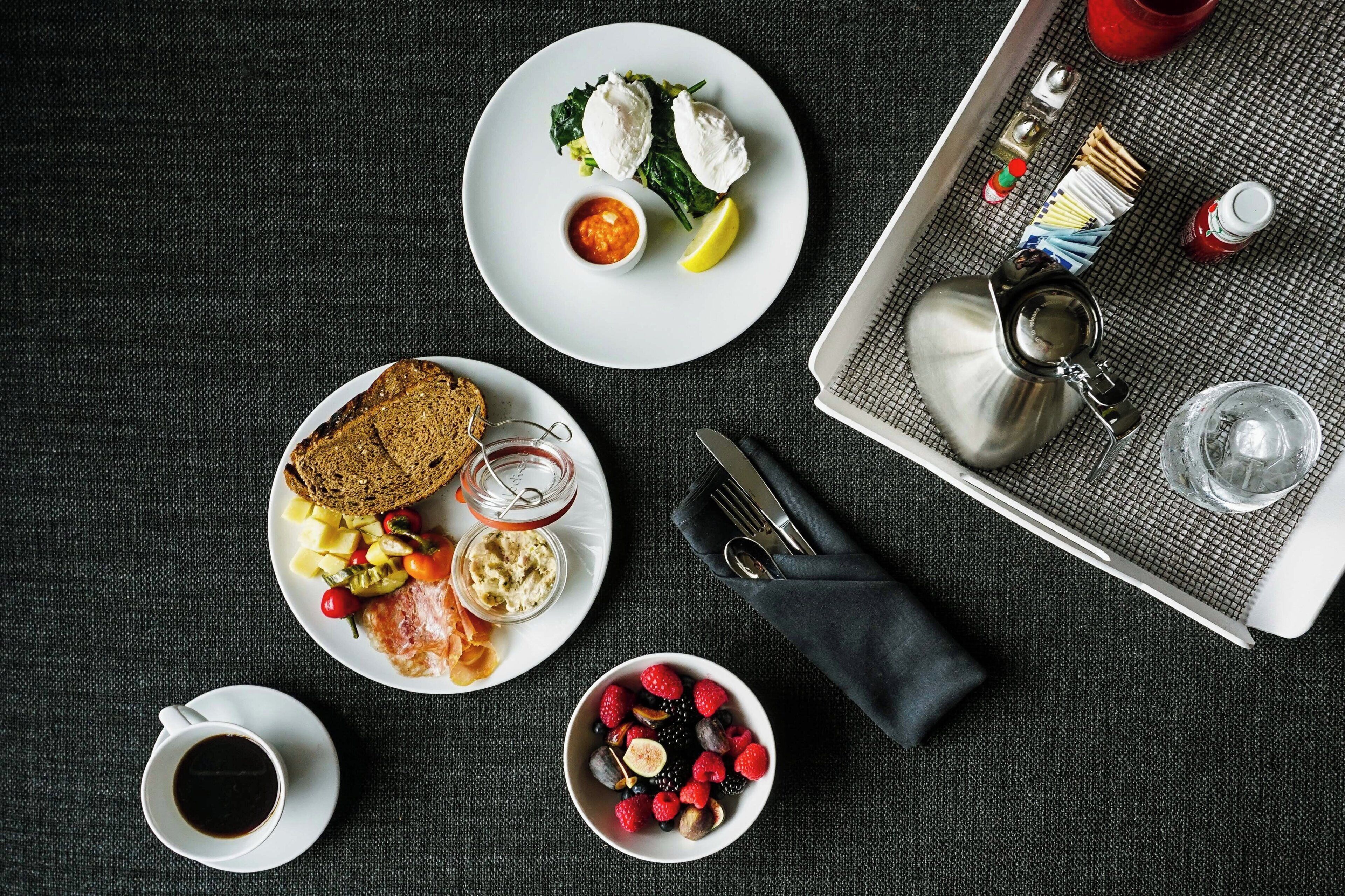 Una colazione servita con piatti di cibo, una tazza di caffè e un vassoio con posate.