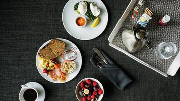 Una colazione servita con piatti di cibo, una tazza di caffè e un vassoio con posate.