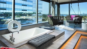 A modern bathroom with a large bathtub, two hanging chairs, and a view of the city. - W Bellevue (Bellevue)