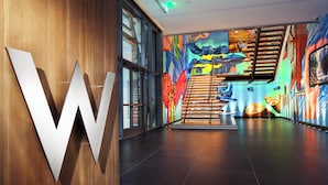 A modern interior with a prominent 'W' logo, a staircase, and colorful murals on the walls. - W Bellevue (Bellevue)