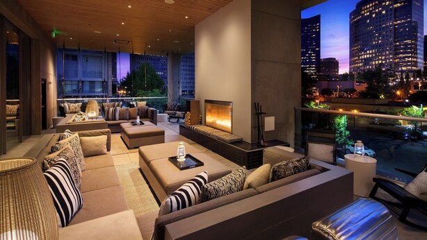 A modern lounge area with sofas, a fireplace, and a city view. - W Bellevue (Bellevue)