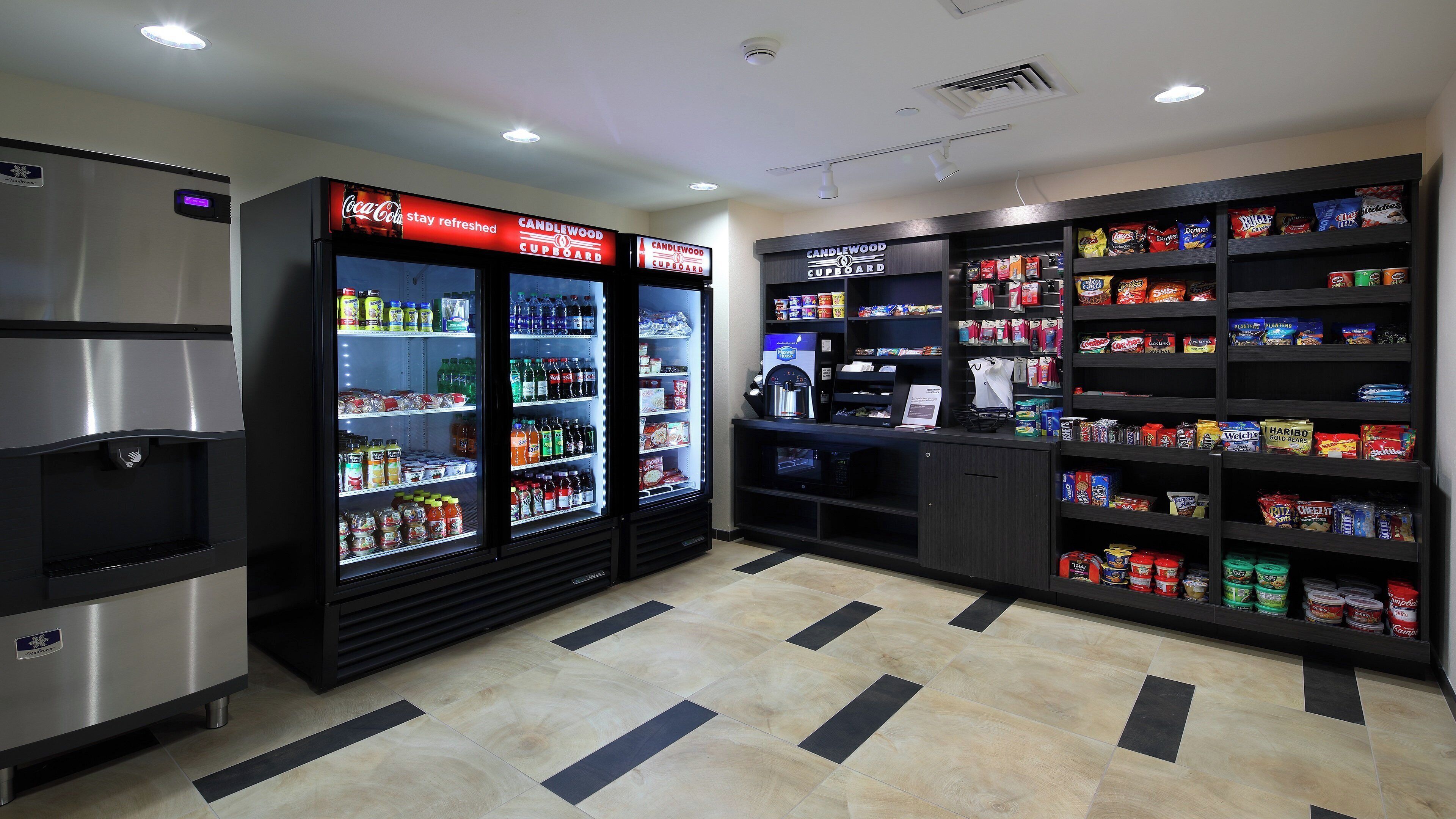 A vending area with refrigerated beverage dispensers, a coffee machine, and shelves stocked with snacks and beverages.