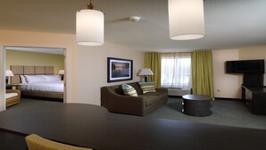 Una habitación de hotel con cama, sofá, televisión y escritorio.