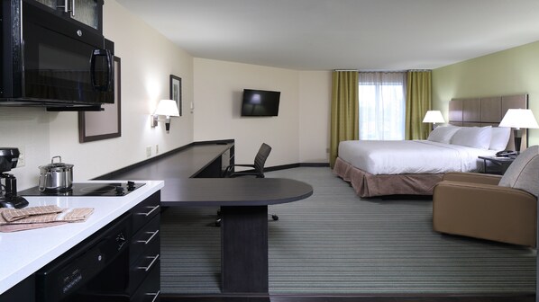 Una habitación de hotel con cama, escritorio, silla, televisor y cafetera.