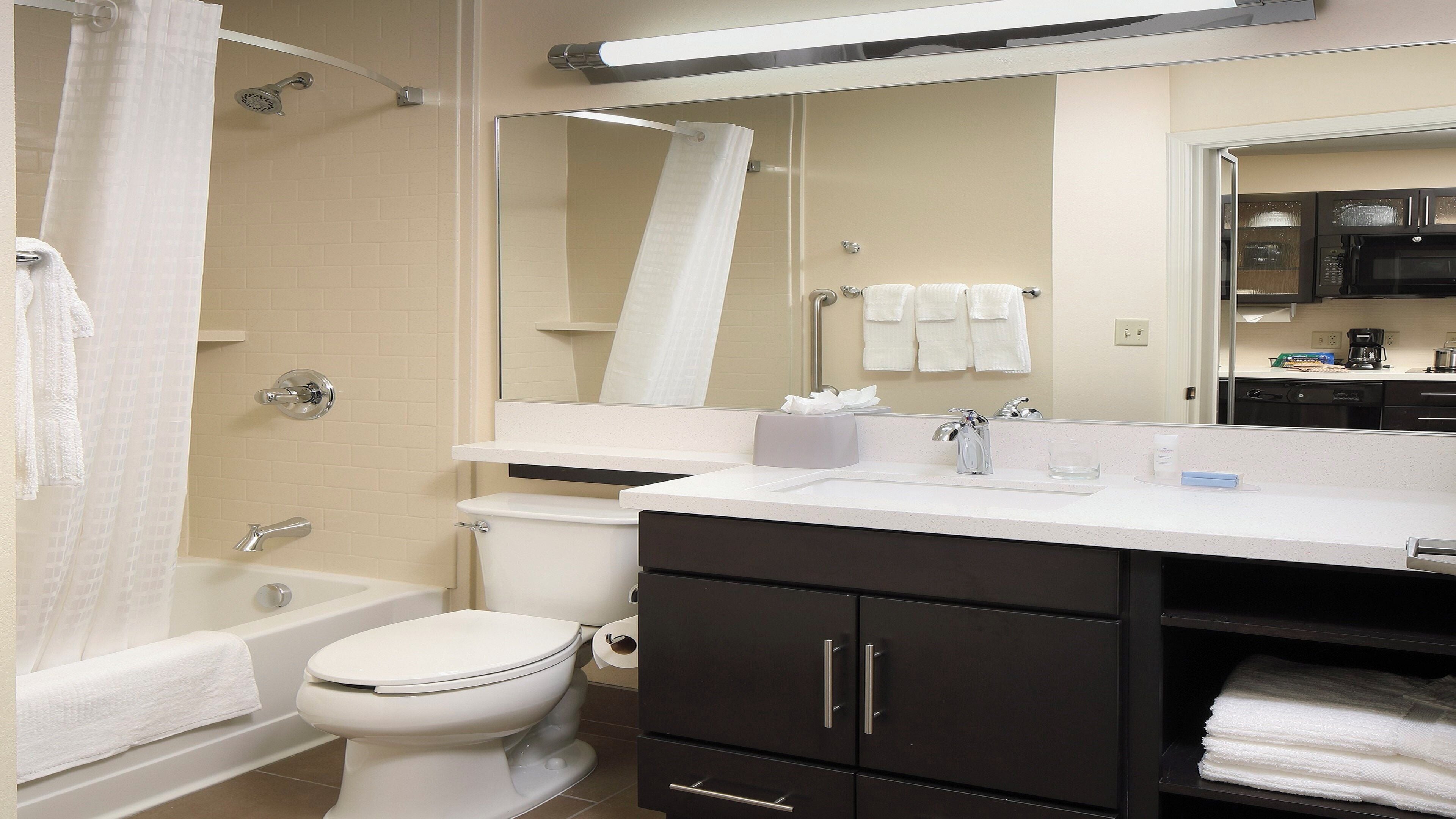 A modern bathroom with a bathtub, toilet, and vanity with a mirror.