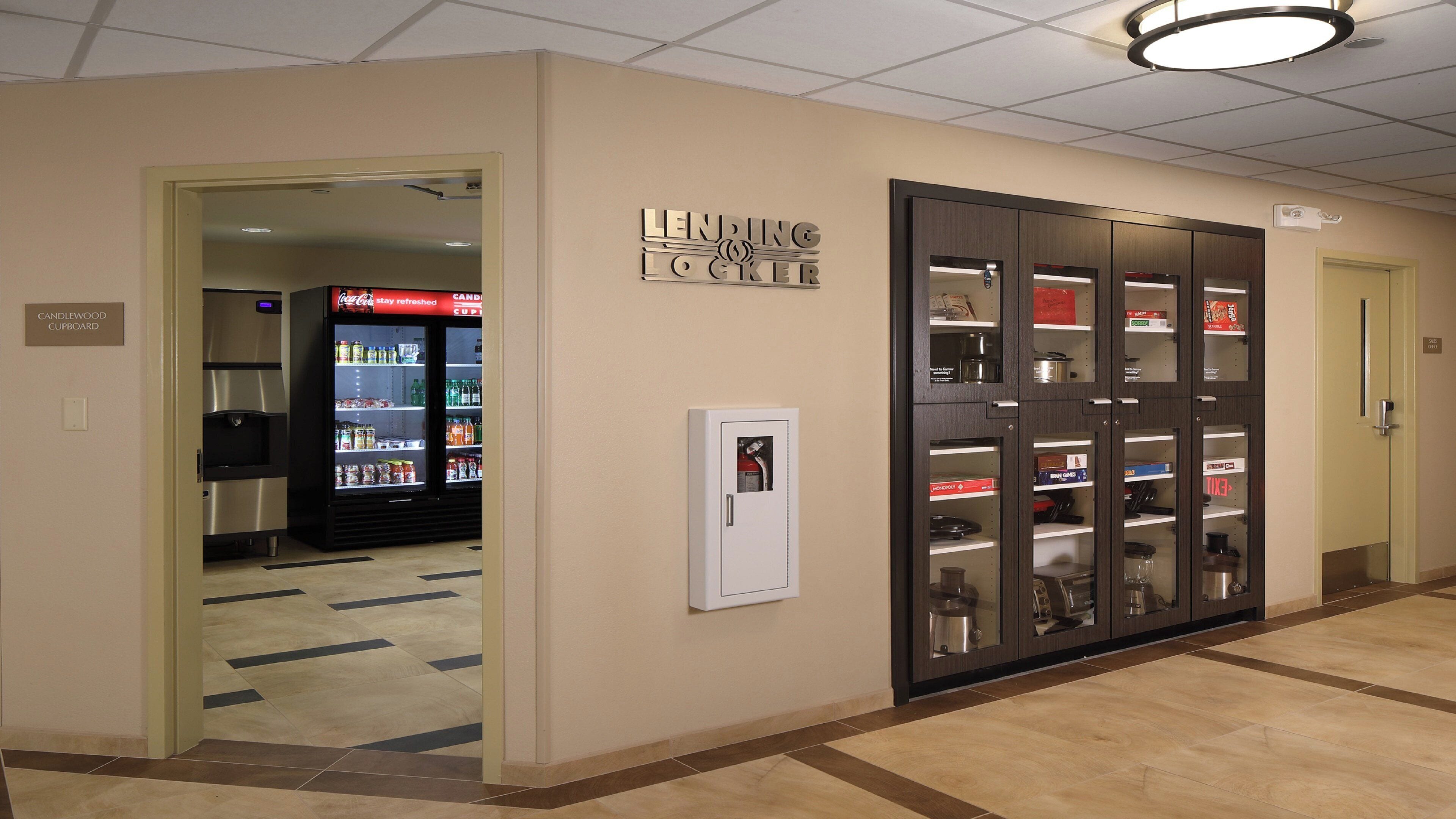 A hallway with a vending machine, a refrigerator, and a cabinet with shelves.