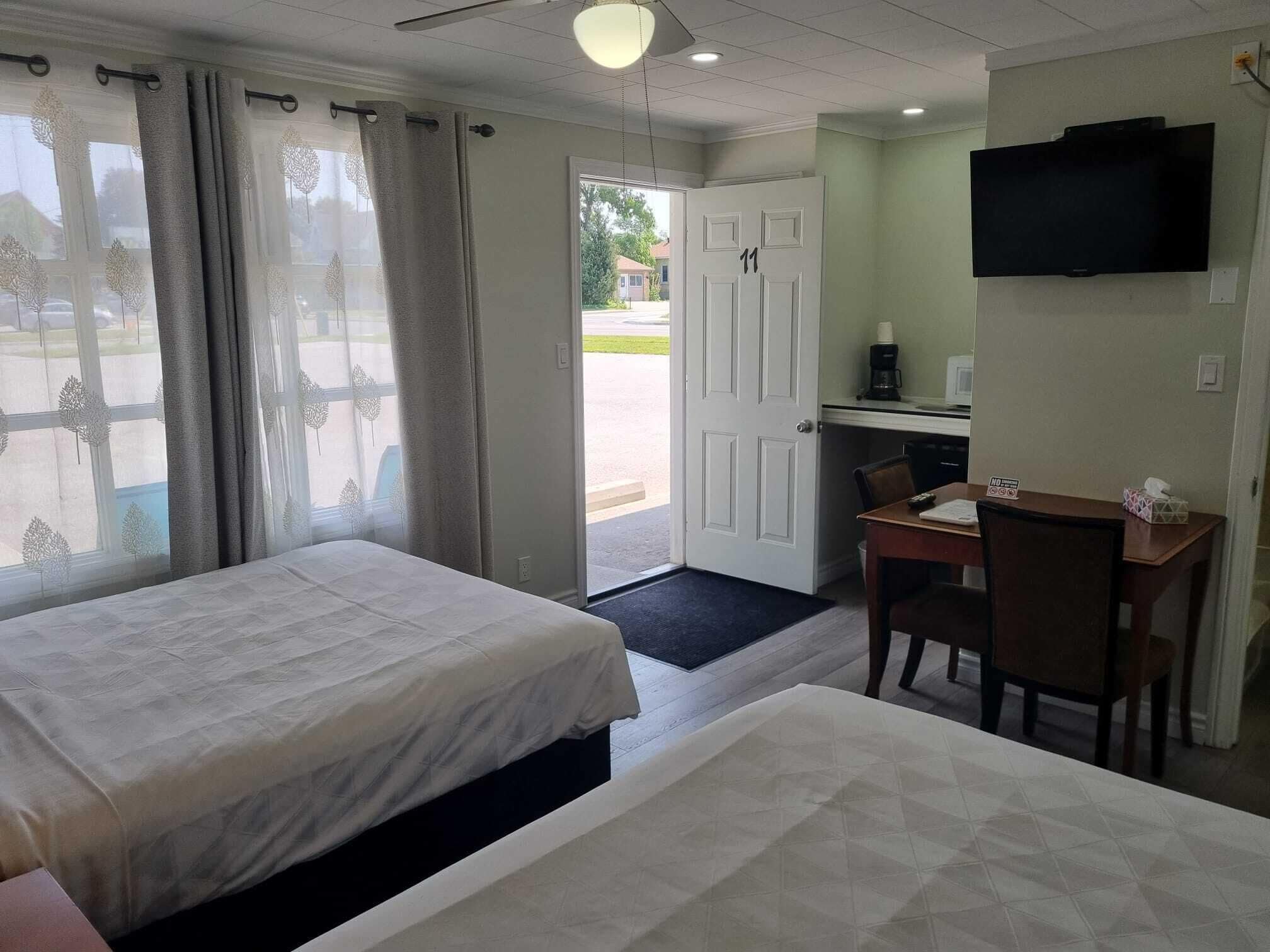 Une chambre d’hôtel avec deux lits, un bureau, une chaise, une télévision et une vue sur l’extérieur.