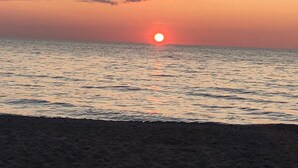 Un atardecer sobre un mar tranquilo con una playa en primer plano.