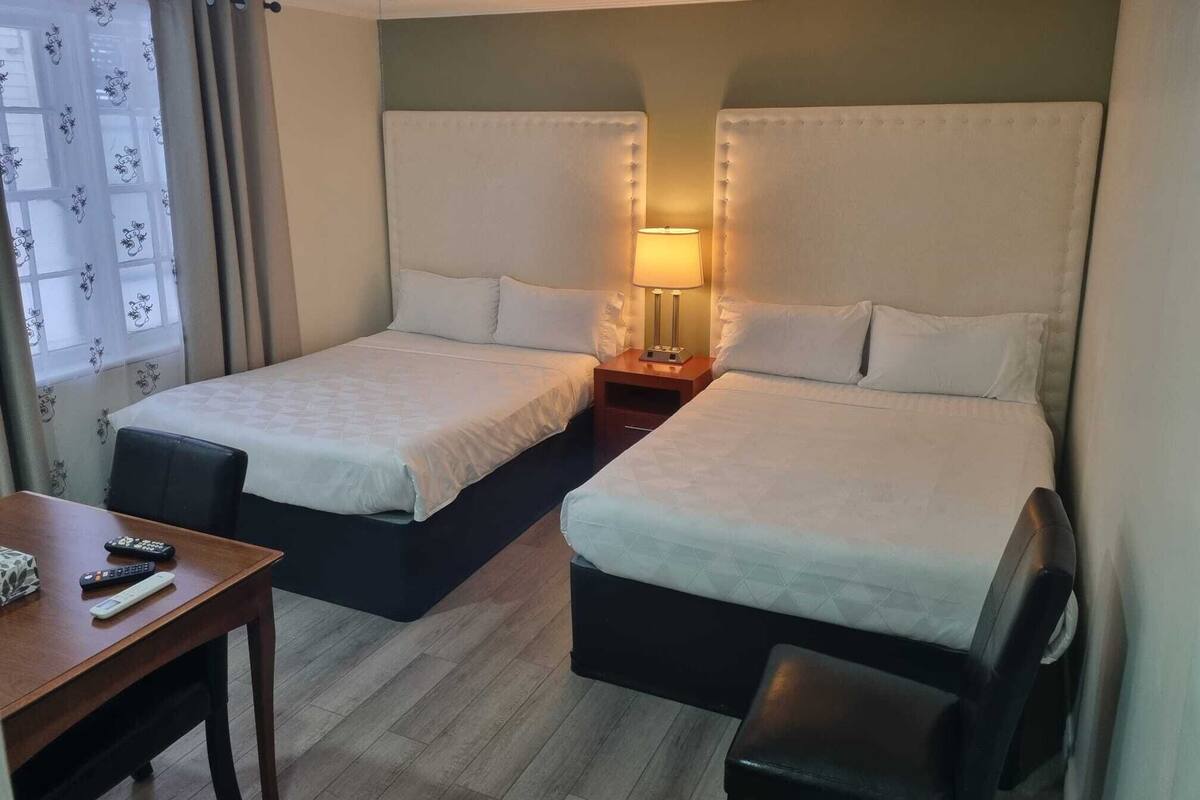 Quarto de hotel com duas camas, uma mesa e uma cadeira.