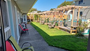 Un patio con mobiliario exterior, una pérgola de madera y una zona de piscina cercada.