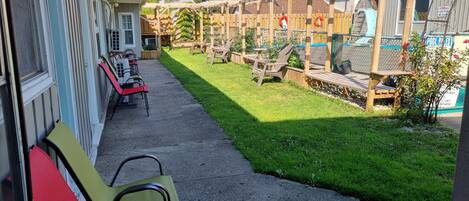 Un patio con mobiliario exterior, una pérgola de madera y una zona de piscina cercada.
