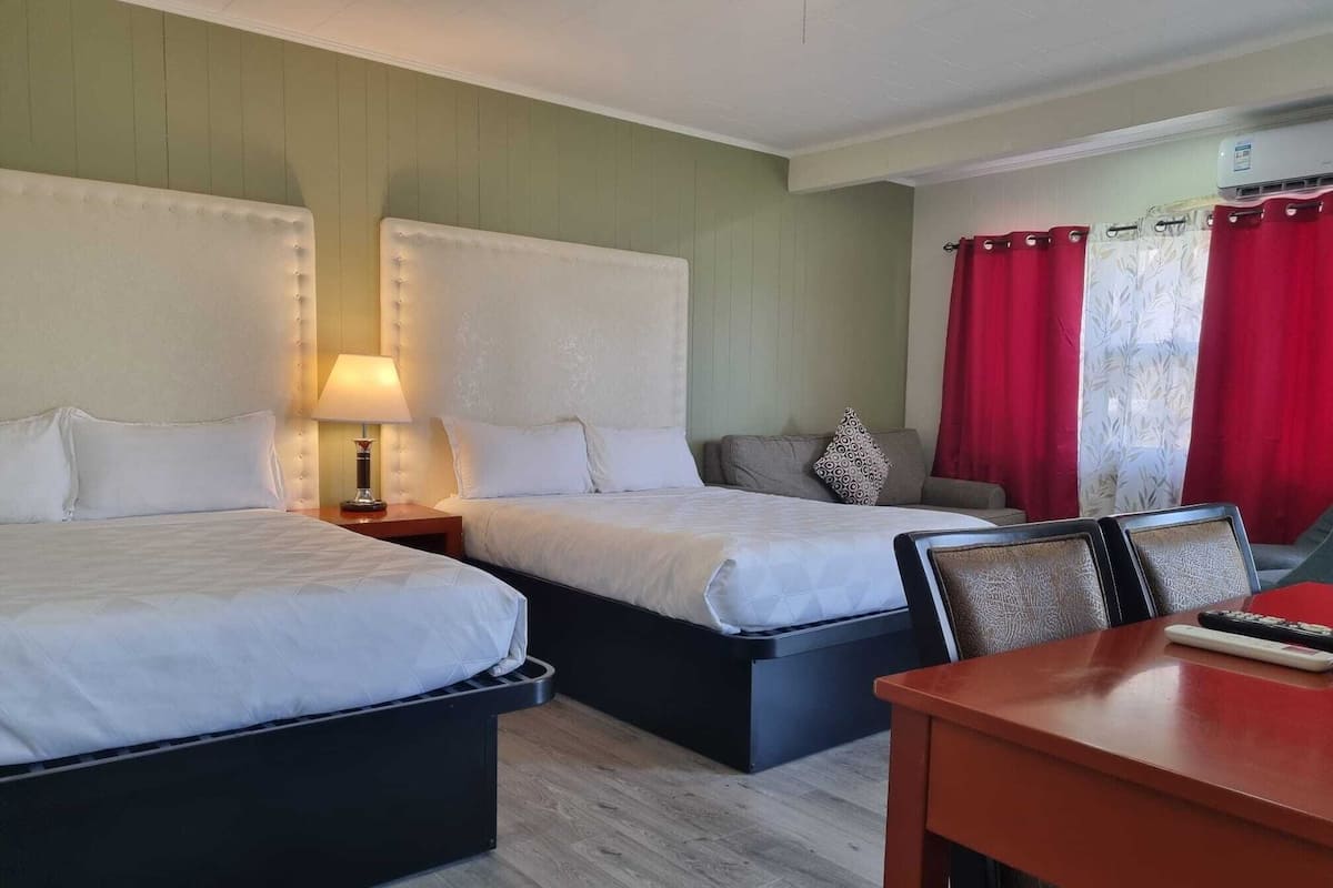 Quarto de hotel com duas camas, uma mesa e uma cadeira.