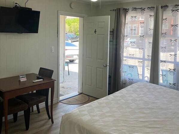 A room with a bed, a desk with a chair, a television, and a door leading outside. - Manor Motel (Saugeen Shores)