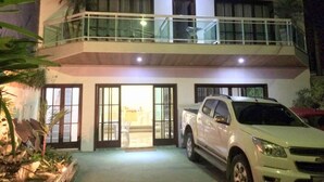 A two-story building with a balcony on the upper floor, a white pickup truck parked in front, and a sign indicating a business or service.