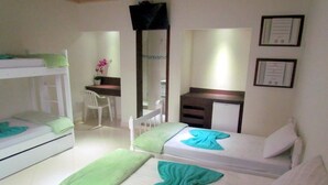 A hotel room with two single beds, a desk, a chair, a mirror, and a small cabinet.