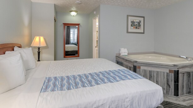 Une chambre d’hôtel avec un grand lit, une salle de bain avec une baignoire et un miroir.
