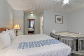 Ein Hotelzimmer mit einem großen Bett, einem Badezimmer mit Badewanne und einem Spiegel.