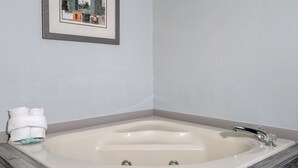 Une salle de bain avec une grande baignoire, un tableau encadré au mur et un porte-serviettes avec des serviettes.