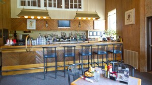 A bar area with wooden paneling, a television mounted above the bar, and multiple chairs and tables. - Club Wyndham Smugglers’ Notch Vermont  (Jeffersonville)