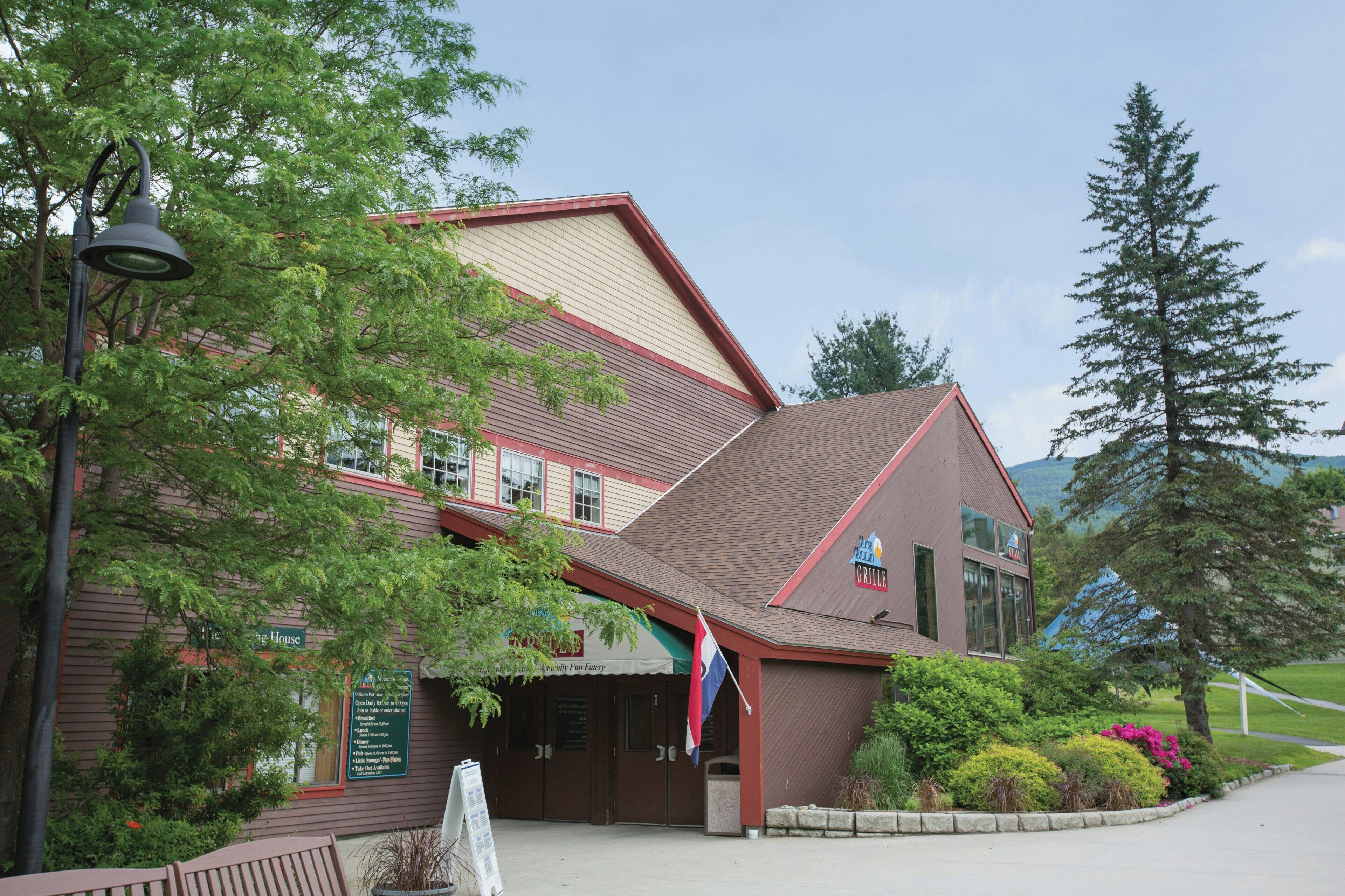 A building with a brown roof and red trim, a sign for a restaurant, and a flagpole with a flag.
