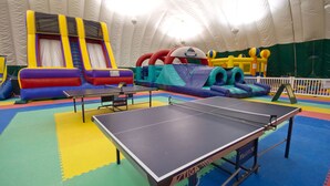 An indoor play area with a ping pong table, inflatable slides, and play structures. - Club Wyndham Smugglers’ Notch Vermont  (Jeffersonville)