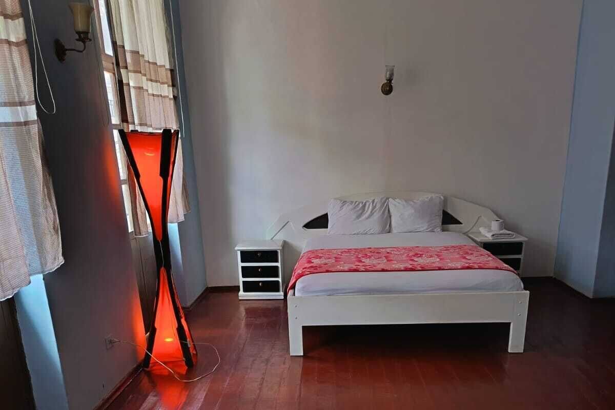 Um quarto com uma cama, uma mesa de cabeceira, uma mesa de vidro e uma cadeira.