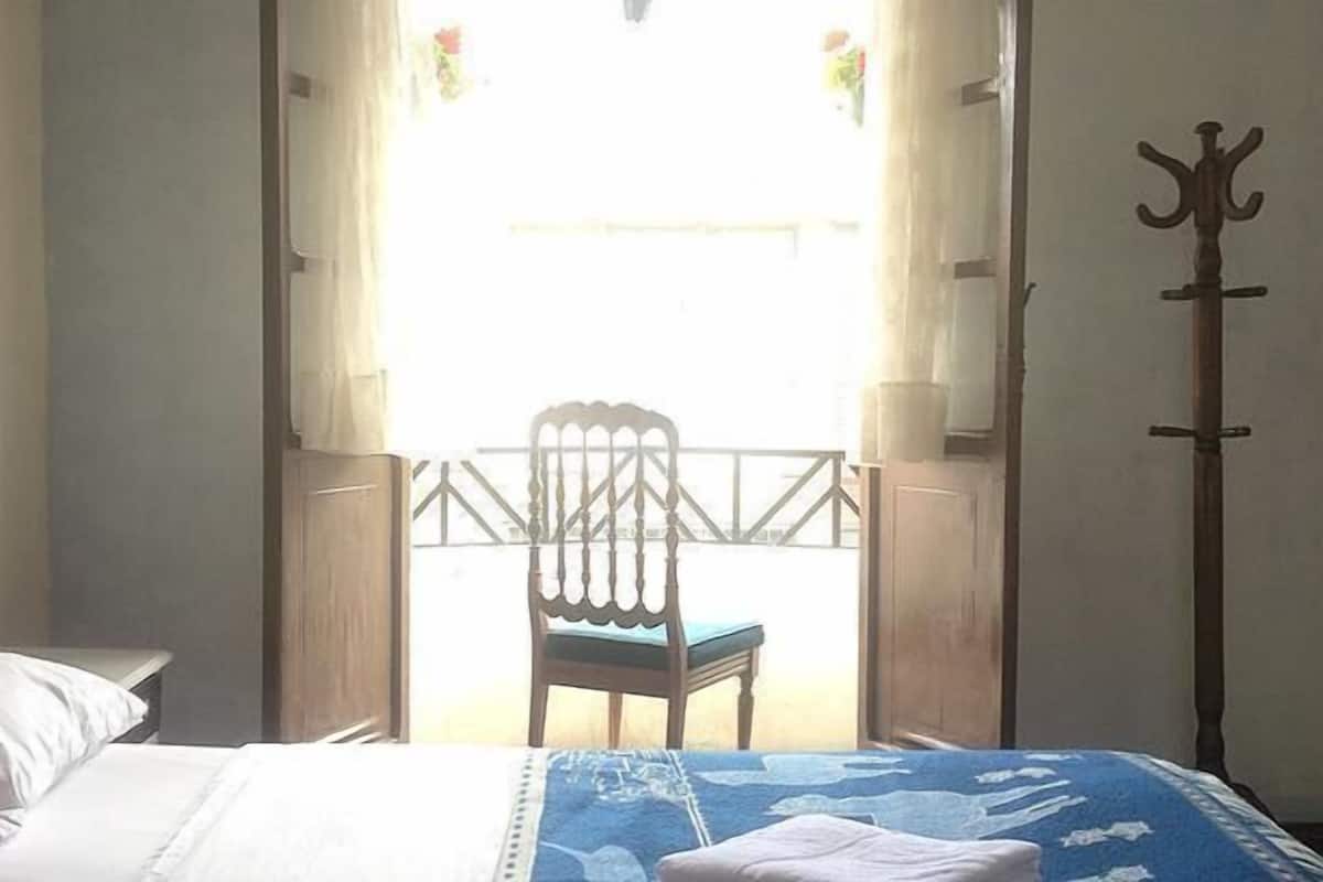 Um quarto com uma cama, uma cadeira e um cabideiro.