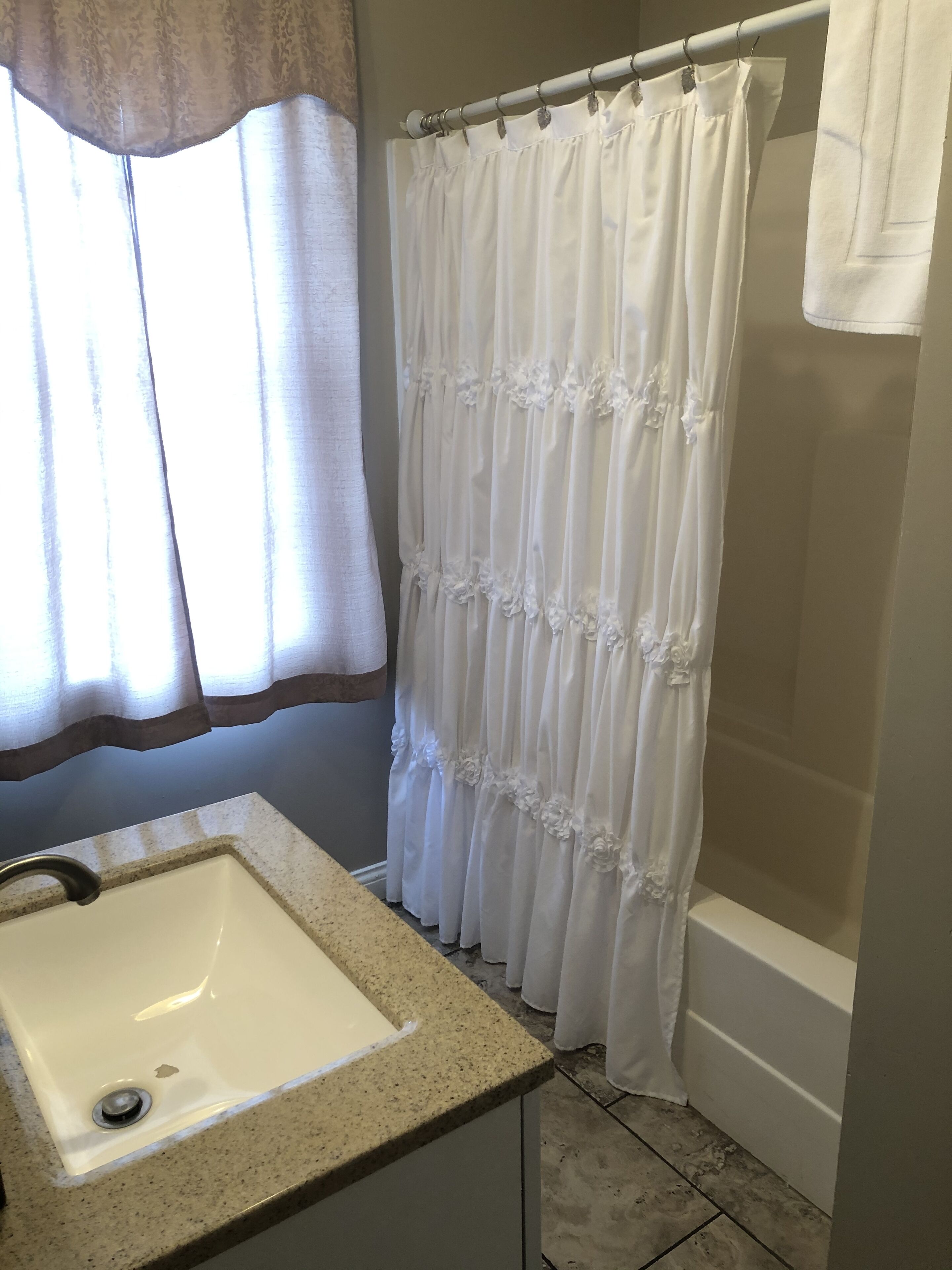 A bathroom with a white sink, a shower curtain, and a bathtub.