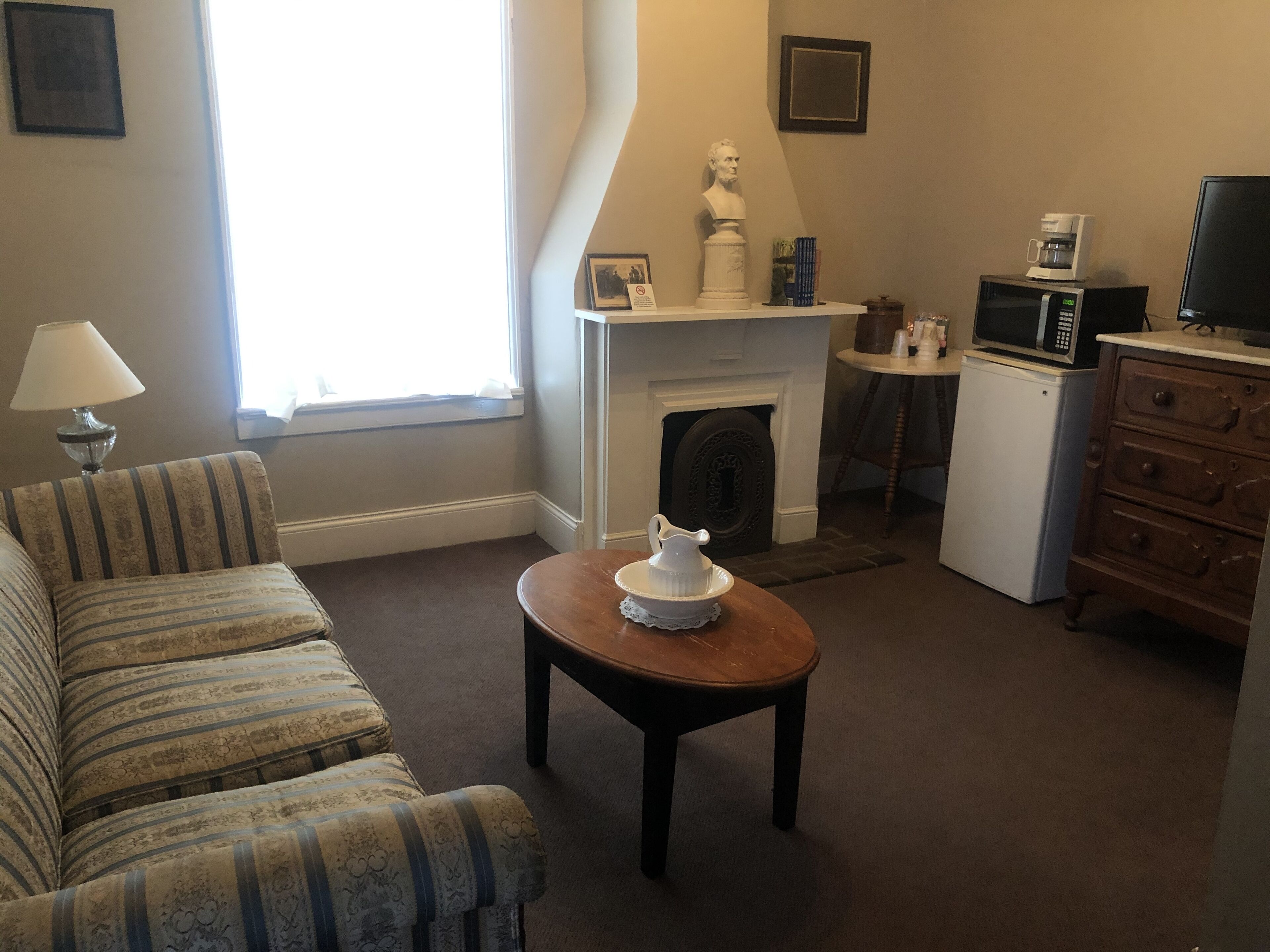 A living room with a sofa, a coffee table, a fireplace, a television, and a microwave.