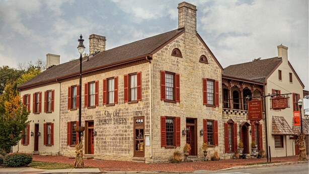 A historic building with red shutters, stone walls, and a sign indicating it is a tavern. - Talbott Inn (Bardstown)
