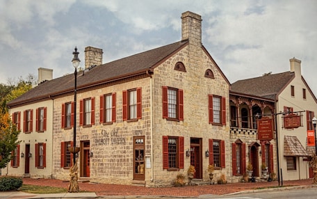 A historic building with red shutters, stone walls, and a sign indicating it is a tavern.