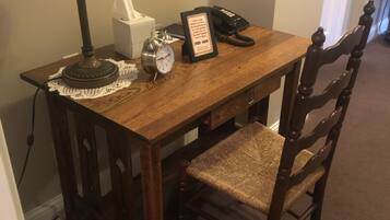 Een houten eettafel met een kantonderzetter, een klok, een tissuedoos, een lijst met een bord en een telefoon.