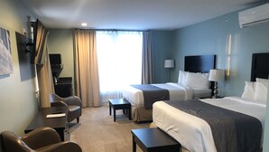A hotel room with two beds, a desk, a chair, a small table, and a TV. - Talbott Inn (Bardstown)