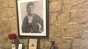 A fireplace with a framed photograph above it, a small plaque, a bottle, and a vase on the mantel. - Talbott Inn (Bardstown)