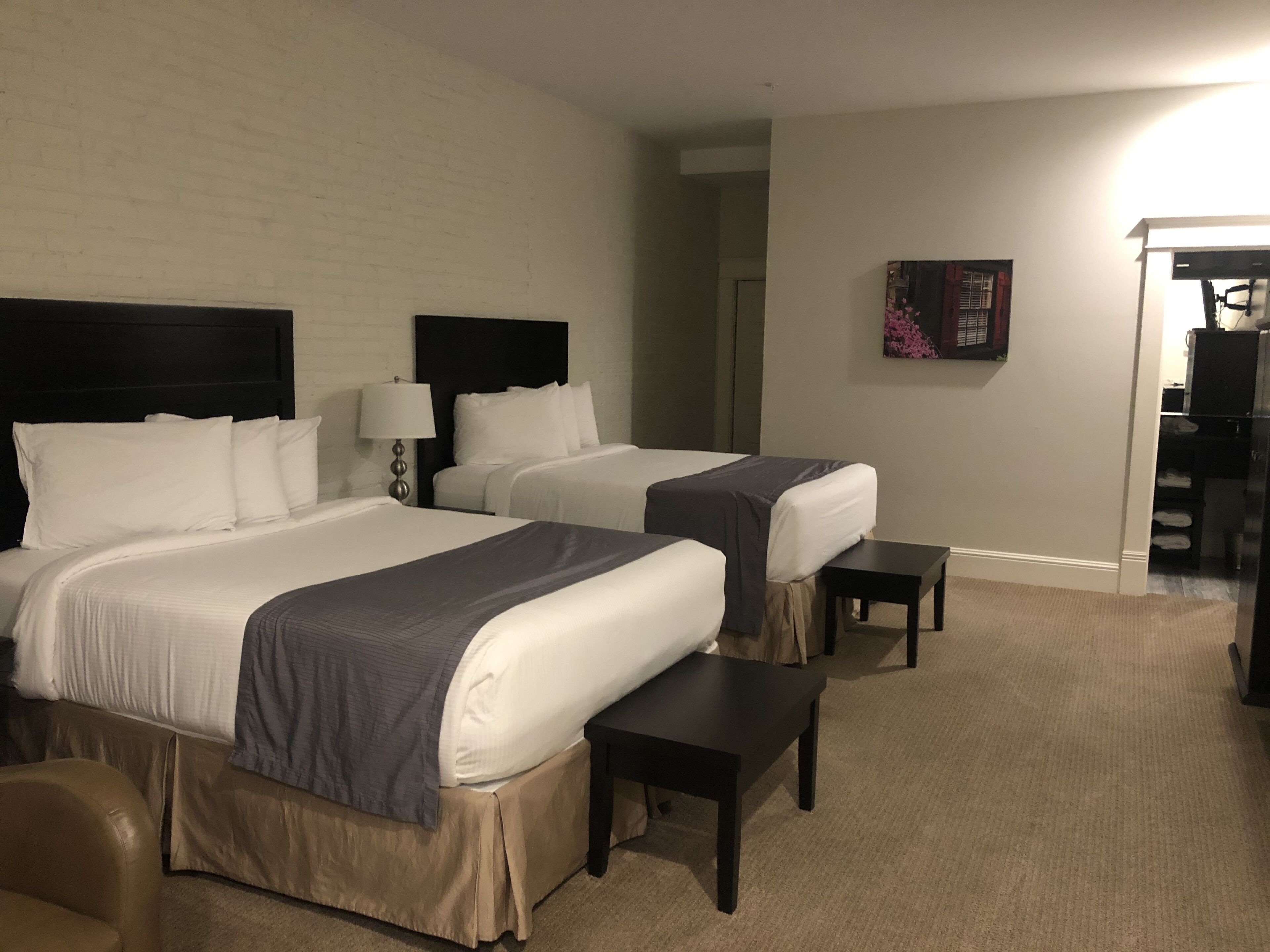Una habitación de hotel con dos camas, un escritorio, una silla y una mesita.