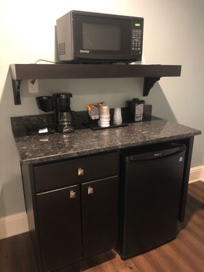 A compact kitchen with a microwave, coffee maker, and a refrigerator.