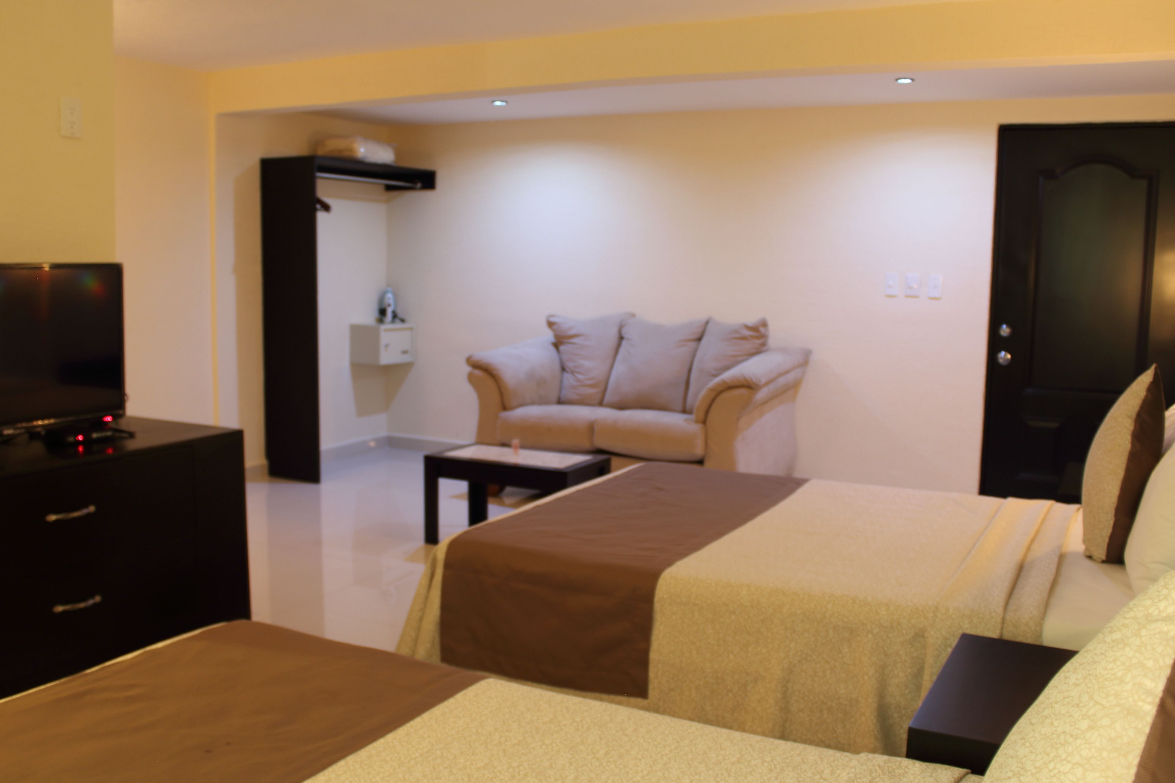 Habitació d'hotel amb dos llits, televisió, taula petita i sofà.