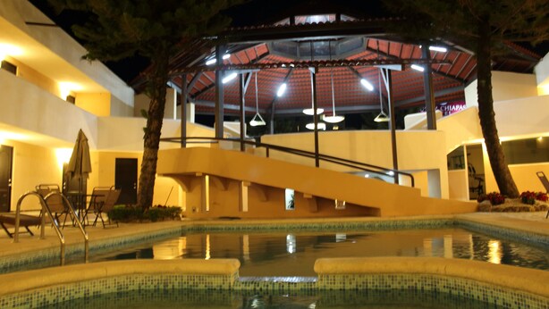 Un área de piscina con zona de estar techada, escaleras y vistas al exterior del edificio.