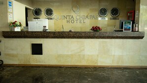 Mostrador de recepción del Hotel Quinta Chiapas con relojes que muestran la hora de Nueva York, Londres y Tokio.