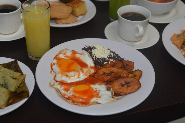 Desayuno servido con platos de comida, incluyendo huevos, plátanos maduros y una bebida.