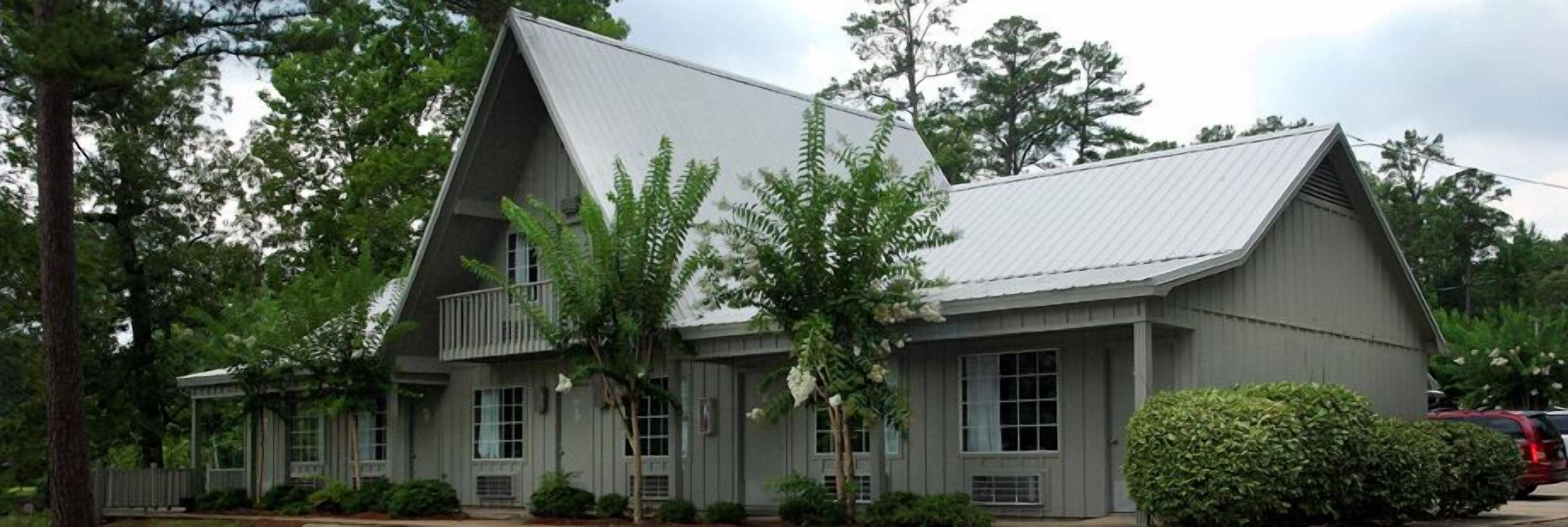 A two-story building with a gabled roof, large windows, and a porch area.