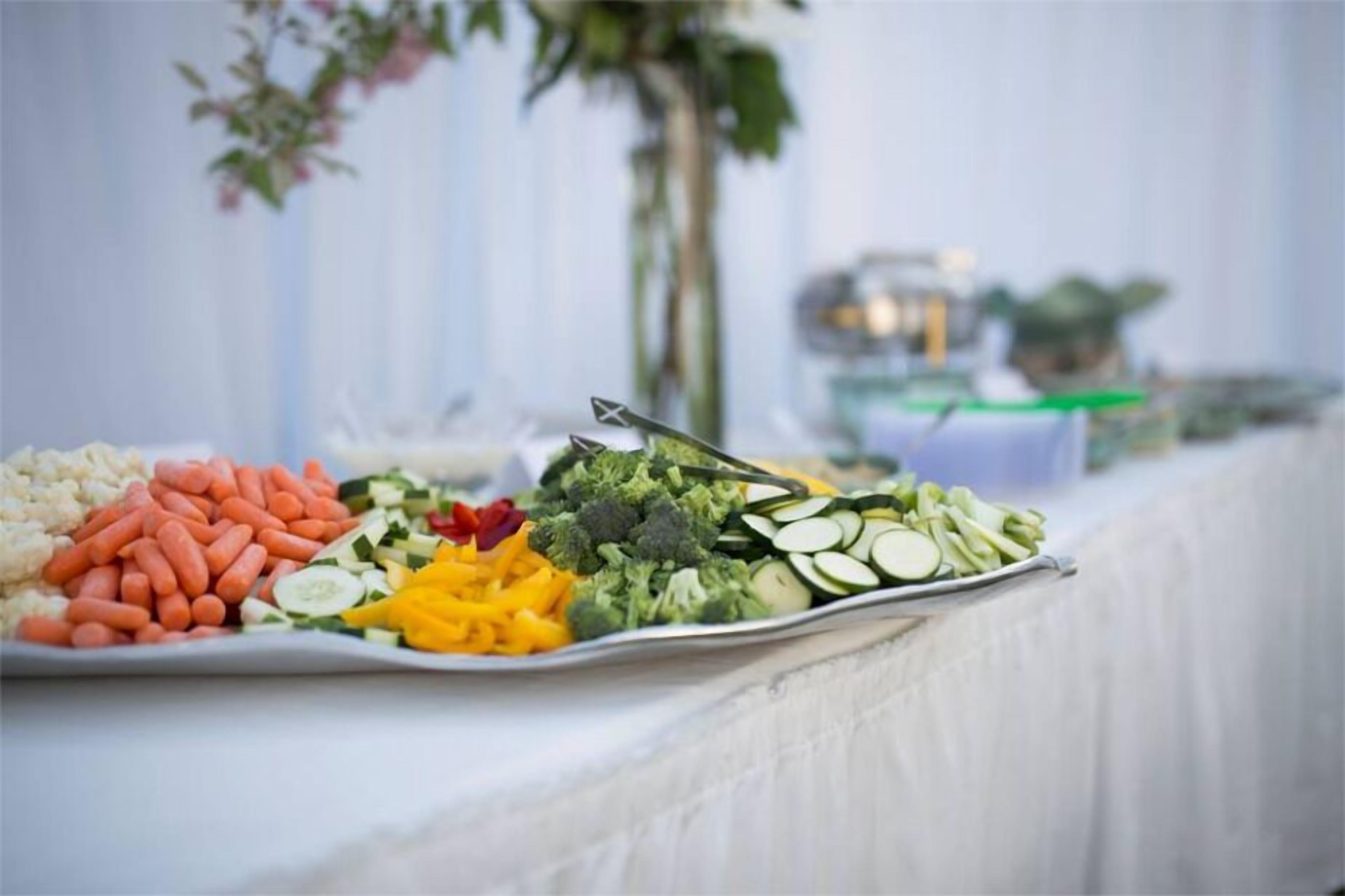 A buffet table with various vegetables and fruits.